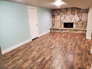 Unfurnished living room featuring wood finished floors, a fireplace, and baseboards