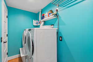 Laundry room featuring washer and dryer, wood finished floors, and baseboards
