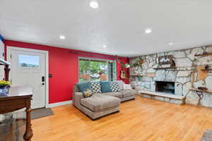 Living area with wood finished floors, baseboards, recessed lighting, and a stone fireplace