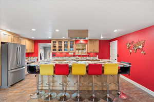 Kitchen with freestanding refrigerator, recessed lighting, a large center island, and glass insert cabinets