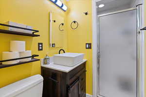 Bathroom featuring a shower stall, vanity, and toilet