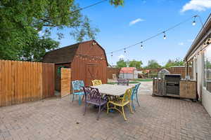 View of patio featuring an outdoor structure, outdoor dining area, a storage shed, and a fenced backyard