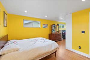 Bedroom with wood finished floors, recessed lighting, a large walk-in closet, and baseboards
