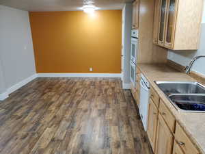 Kitchen featuring a sink, double oven, dark wood finished floors, and light brown cabinets