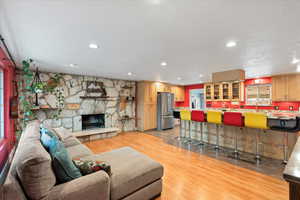 Living area with light wood-style flooring, large island, recessed lighting, and a fireplace