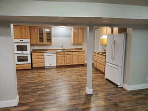 Kitchen with white appliances, a sink, baseboards, under cabinet range hood