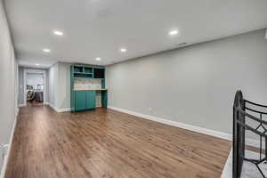 Unfurnished living room featuring dark wood-style flooring, baseboards, and recessed lighting