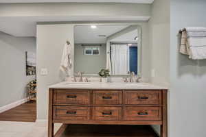 Full bathroom featuring double vanity, baseboards, and tile patterned flooring
