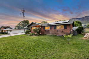 View of front of property with brick siding, solar panels, concrete driveway, and cooling unit