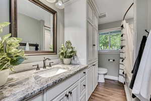 Bathroom with toilet, vanity, wood finished floors, and baseboards