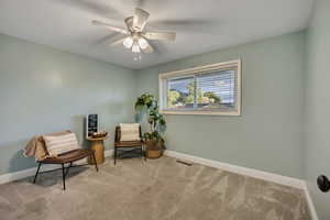 Living area with carpet, baseboards, and a ceiling fan