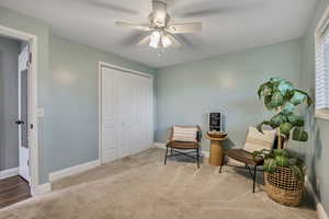 Living area with ceiling fan, baseboards, and carpet floors