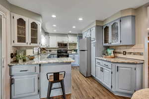 Kitchen with appliances with stainless steel finishes, a peninsula, backsplash, a sink, and wood finished floors