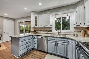 Kitchen with a sink, stainless steel dishwasher, gray cabinetry, white cabinets, and a peninsula