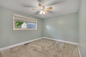 Carpeted empty room with a ceiling fan and baseboards