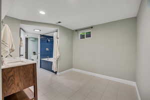 Bathroom featuring baseboards, toilet, double vanity, curtained shower, and tile patterned floors