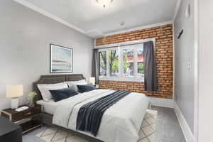 Carpeted bedroom with brick wall, a textured ceiling, ornamental molding, and baseboards