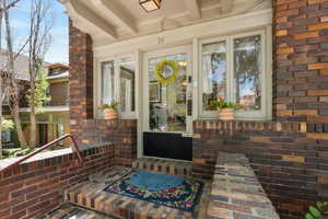 Doorway to property featuring brick siding and a porch