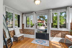 Sunroom featuring wood finished floors, baseboards, and brick wall