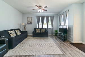 Living area with a ceiling fan, wood finished floors, and baseboards