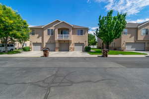 View of property with stucco siding, stone siding, an attached garage, and driveway