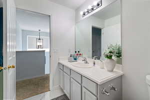 Bathroom with vanity, marble finish flooring, toilet, and a chandelier