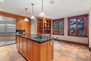 Kitchen with stainless steel appliances, a sink, baseboards, recessed lighting, and dark stone countertops