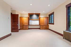 Spare room featuring radiator heating unit, light colored carpet, baseboards, and recessed lighting