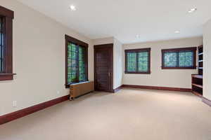 Carpeted empty room with radiator, baseboards, and recessed lighting