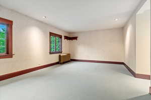 Empty room featuring radiator, carpet floors, recessed lighting, and baseboards