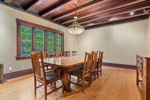Dining area featuring beamed ceiling, baseboards, wood ceiling, a chandelier, and light wood finished floors
