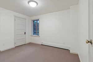 Empty room featuring a baseboard radiator, carpet flooring, and baseboards
