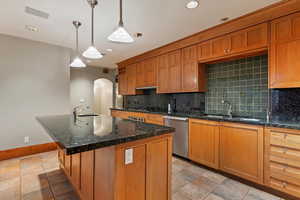 Kitchen with stainless steel dishwasher, a sink, arched walkways, decorative backsplash, and recessed lighting