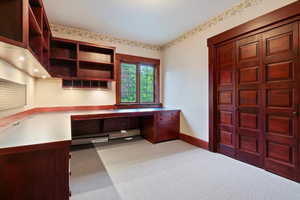 Unfurnished office with built in study area, carpet flooring, baseboards, and baseboard heating