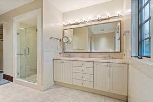Bathroom featuring a shower stall, double vanity, and tile patterned flooring