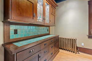 Detailed view of radiator, wood finished floors, and tasteful backsplash