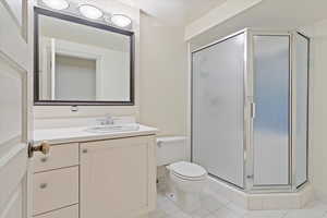 Bathroom with toilet, tile patterned flooring, a stall shower, and vanity