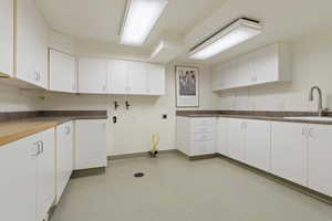 Kitchen with a sink, white cabinets, and baseboards
