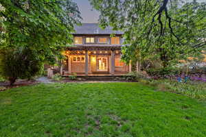 Back of house at dusk featuring a lawn and covered porch