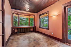 Empty room featuring radiator, wood finished floors, wood ceiling, and baseboards