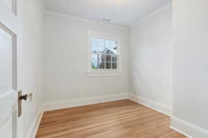 Unfurnished room featuring ornamental molding, light wood finished floors, and baseboards