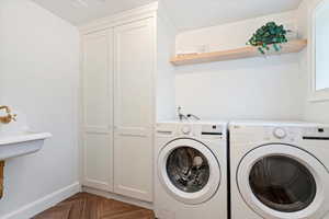 Clothes washing area with washing machine and clothes dryer, cabinet space, and baseboards