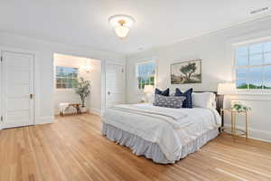 Bedroom with crown molding, light wood-style floors, and baseboards