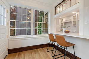 Kitchen featuring baseboards, backsplash, light wood-style floors, a kitchen breakfast bar, and ornamental molding