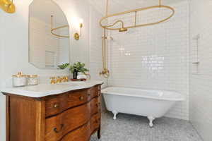 Bathroom with a soaking tub, vanity, a shower, and tile walls