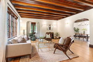 Living room with arched walkways, beamed ceiling, a chandelier, wood finished floors, and wood ceiling