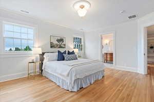 Bedroom with ornamental molding, baseboards, light wood finished floors, and connected bathroom