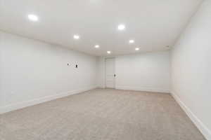Empty room featuring recessed lighting, light colored carpet, and baseboards