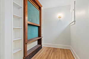 Hall featuring wood finished floors, baseboards, and crown molding