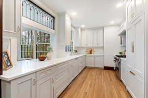 Kitchen featuring stainless steel range, backsplash, light wood-style flooring, white cabinetry, and recessed lighting